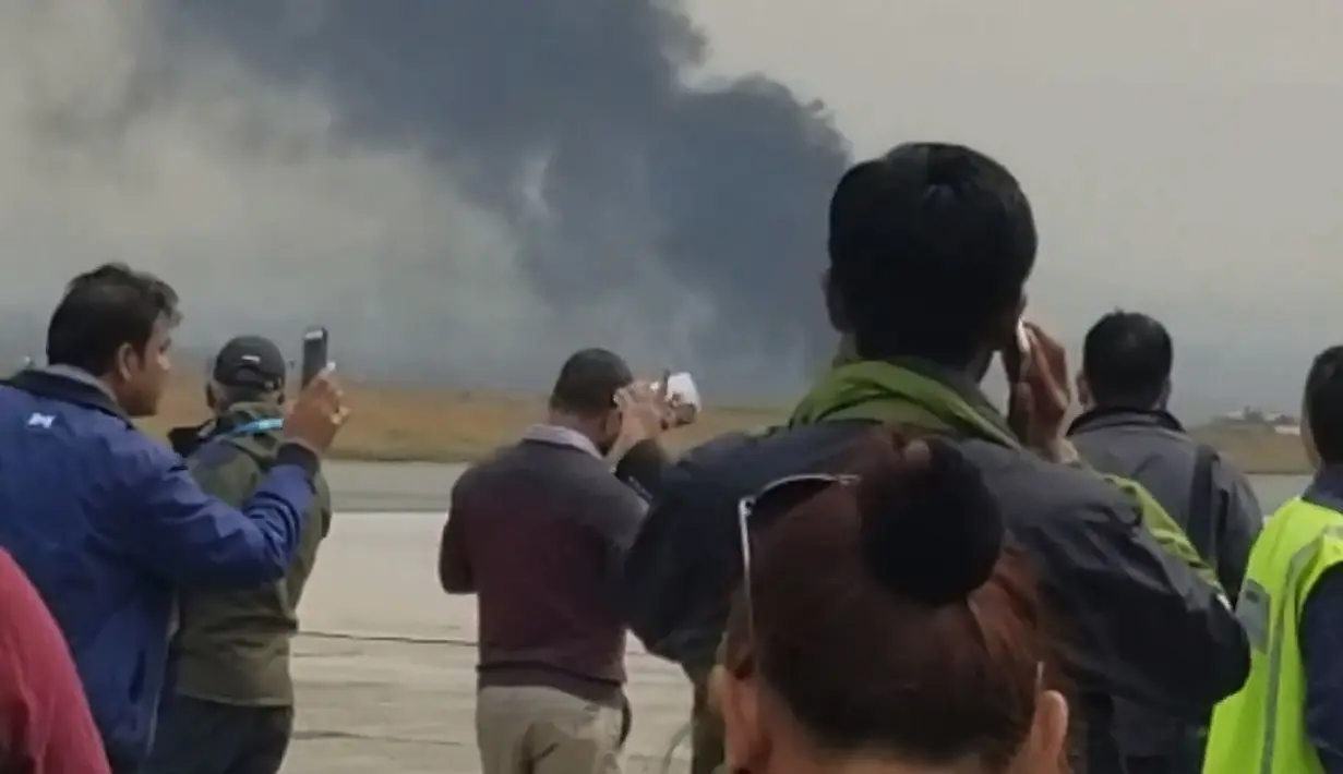 Asap tebal membungbung saat pesawat jatuh dan terbakar di dekat Bandara Internasional Kathmandu, Nepal, Senin (12/3). Menurut manajer bandara, kecelakaan diduga karena pesawat mendekati landasan pacu dari arah yang salah. (Nitin KEYAL/AFP)