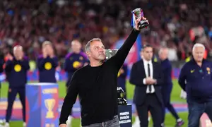 Pelatih kepala Barcelona, Hansi Flick, mengangkat trofinya ke langit sambil merayakan kemenangan setelah mengalahkan Real Madrid 2-0 untuk menjuarai liga sepak bola Spanyol (La Liga) dengan tiga pertandingan tersisa, di Barcelona, Spanyol, Minggu, 10 Mei 2026. (AP Photo/Joan Mateu Parra)