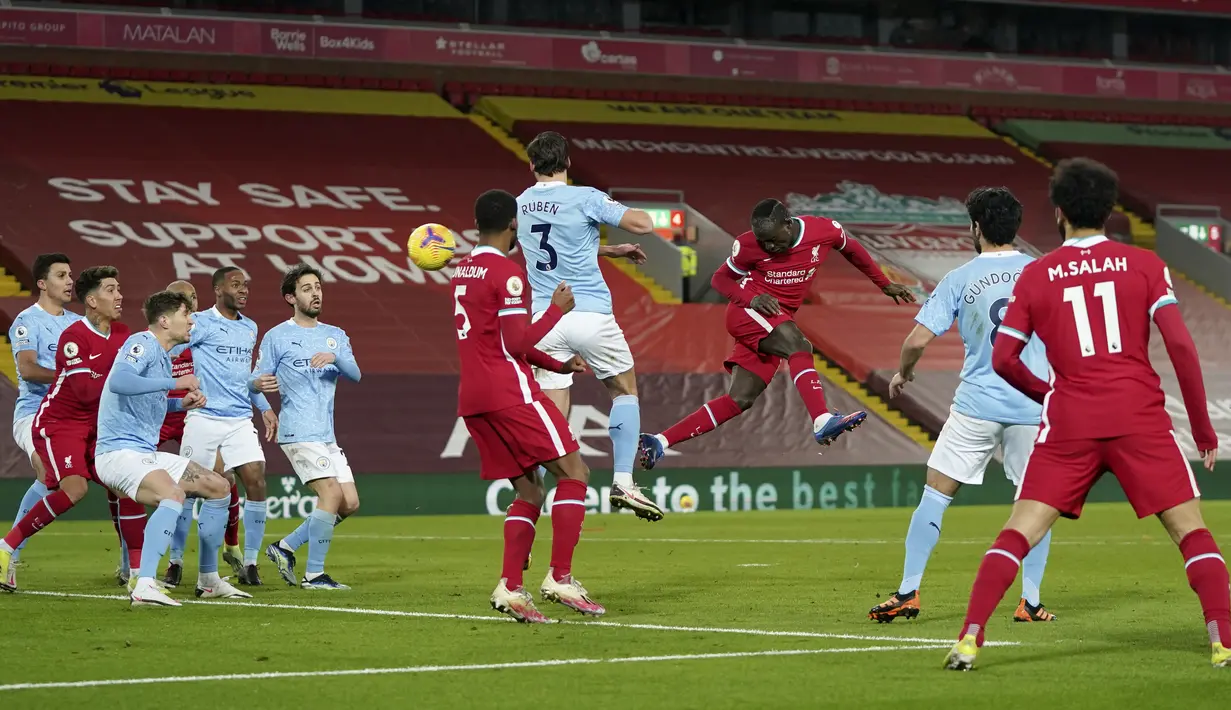 Penyerang Liverpool, Sadio Mane (kanan tengah) berusaha menyundul bola ke arah gawang Manchester City pada pertandingan lanjutan Liga Inggris di Stadion Anfield, Inggris, Senin (8/2/2021).  Hasil ini membuat posisi City kokoh di puncak klasemen sementara dengan 50 poin. (AP photo/Jon Super, Pool)