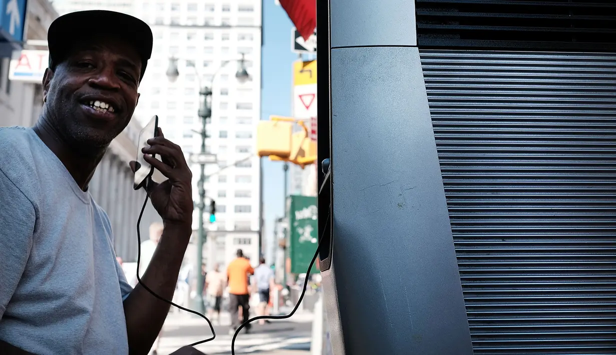 Maurice Rilay menggunakan salah satu kios Wi-Fi gratis di Manhattan, New York, 24 Agustus 2016. Proyek LinkNYC ini menyulap sejumlah telepon umum usang menjadi kios Wi-Fi gratis untuk bisa mengakses internet, menelepon dan pengisian baterai ponsel. (AFP)