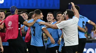 Gelandang Uruguay, Manuel Ugarte (tengah) merayakan dengan rekan setimnya setelah mencetak gol dalam adu penalti untuk memenangkan pertandingan perempat final Copa America 2024 melawan Brasil di Stadion Allegiant, Las Vegas, Nevada pada 6 Juli 2024 atau Minggu 7 Juli 2024 WIB. (Robyn BECK/AFP)