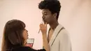 Penata rias memakaikan make up pada Han Hyun-Min sebelum menjalani sesi pemotretan di sebuah studio di Seoul, 7 Juli 2017. Model hitam pertama di negeri gingseng itu merupakan remaja keturunan Nigera dan Korea Selatan. (Ed JONES / AFP)