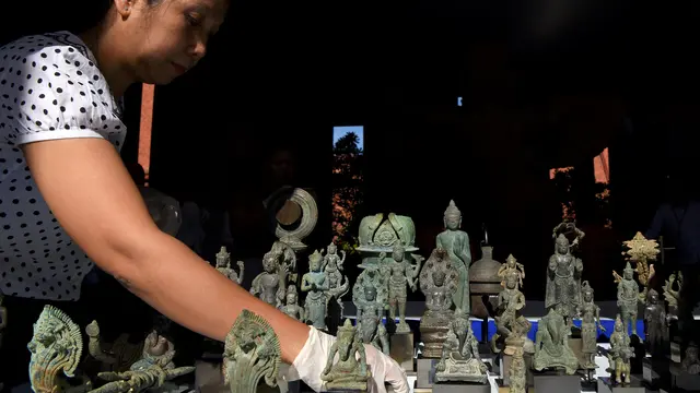 Seorang pegawai museum menyiapkan artefak dalam upacara pengembalian 85 barang ke Museum Nasional di Phnom Penh