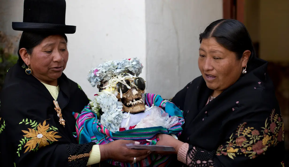 Wanita membawa tengkorak manusia yang dihias usai berdoa di kapel Pemakaman Umum selama Festival Natitas di La Paz, Bolivia (8/11). Ritual ini digelar setiap tahunnya di Bolivia. (AP Photo/Juan Karita)