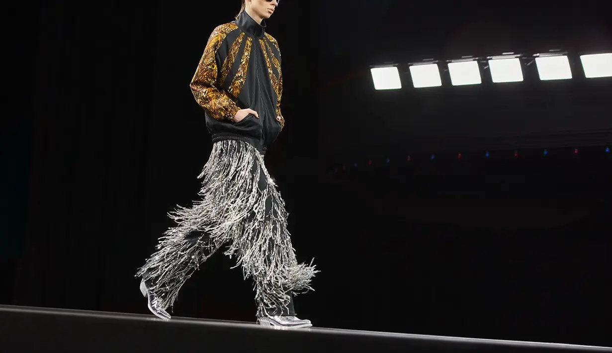 Tak hanya sweater, Slimane juga menghadirkan fringed silver untuk koleksi celana mereka. Penampilan model terlihat semakin standout dengan paduan jaket bomber warna emas-hitam. (Dok/Celine).