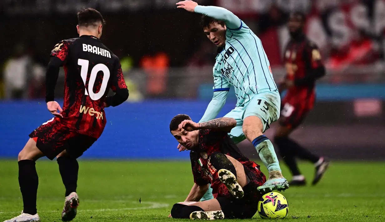 Gelandang AC MilanRade Krunic (bawah) berebut bola dengan gelandang Atalanta Marten de Roon (kanan) pada lanjutan Liga Italia Serie A musim 2022/2023, Senin (27/2/2023) dini hari WIB. Main di kandang sendiri, Stadion San Siro, Milan langsung menekan Atalanta sejak awal. (Marco BERTORELLO / AFP)