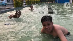 Keseruan anak-anak berenang di kolam penghias taman Pasar Baru di Jakarta, Rabu (2/9/2020). Meskipun terdapat larangan, namun sejumlah anak tetap nekat berenang di kolam tersebut sehingga mengganggu ketertiban umum. (Liputan6.com/Immanuel Antonius)