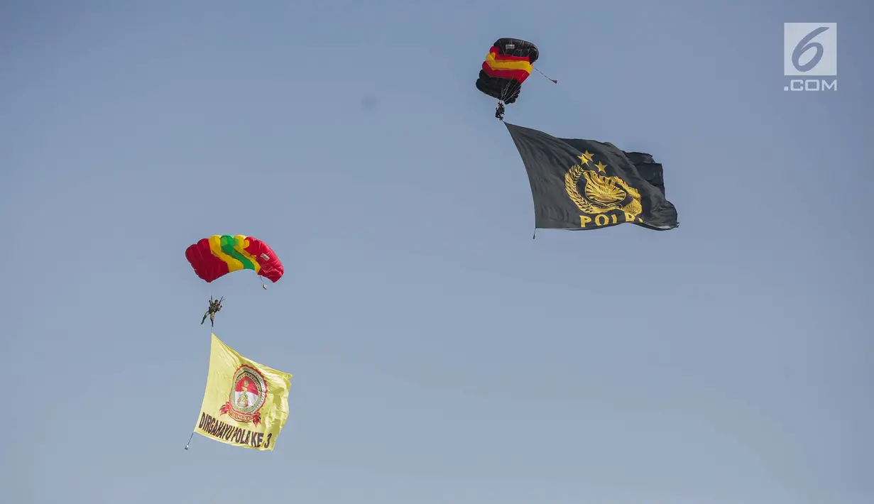 Penerjun payung membawa bendera Polri saat tampil dalam perayaan HUT ke-73 Bhayangkara di Monas, Jakarta, Rabu (10/7/2019). Sebanyak 22 penerjun payung dari TNI dan Polri ikut menyemarakkan HUT ke-73 Bhayangkara. (Liputan6.com/Faizal Fanani)