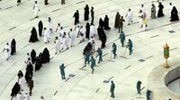 Pekerja melakukan disinfeksi untuk membantu mengekang penyebaran virus corona COVID-19 saat jemaah umrah tawaf mengelilingi Ka'bah pada awal bulan suci Ramadhan di Masjidil Haram, Mekkah, Arab Saudi, Senin (12/4/2021). (AP Photo/Amr Nabil)