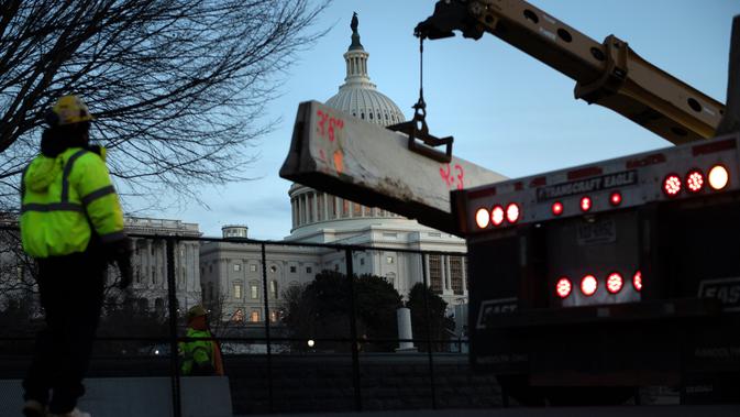 Para pekerja memperkuat pagar pengendali massa di sekitar Capitol Hill AS, Washington D.C, dengan penghalang beton sehari setelah peristiwa kericuhan, Kamis (7/1/2021). Peristiwa penyerbuan di gedung Capitol Hill AS dilakukan oleh massa pendukung Donald Trump pada 6 Januari. (Brendan Smialowski/AFP)