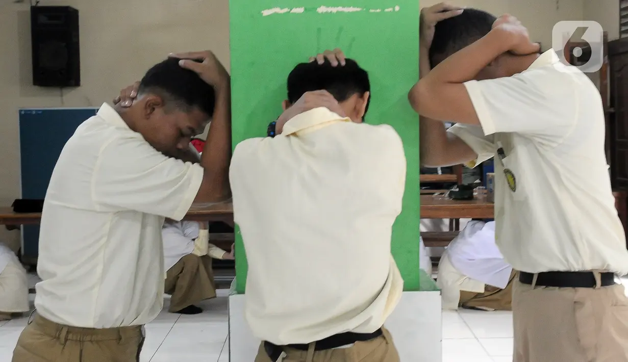 Sejumlah santri melindungi kepada mereka dengan tangan saat pelatihan tanggap bencana dan kebakaran yang dilakukan oleh Badan Penanggulangan Bencana Daerah (BPBD) DKI Jakarta bersama Pemadam Kebakaran DKI Jakarta di Madrasah Aliyah Swasta Persatuan Islam (MAS Persis) 69, Matraman, Jakarta, Selasa (19/9/2023). (merdeka.com/Imam Buhori)