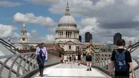 Orang-orang berjalan di Jembatan Milenium dengan latar pemandangan Katedral St. Paul di London, Inggris, 1 Agustus 2020. Pemerintah Inggris pada Jumat (31/7) mengumumkan penundaan pelonggaran beberapa langkah pembatasan menyusul jumlah infeksi virus corona yang meningkat. (Xinhua/Han Yan)