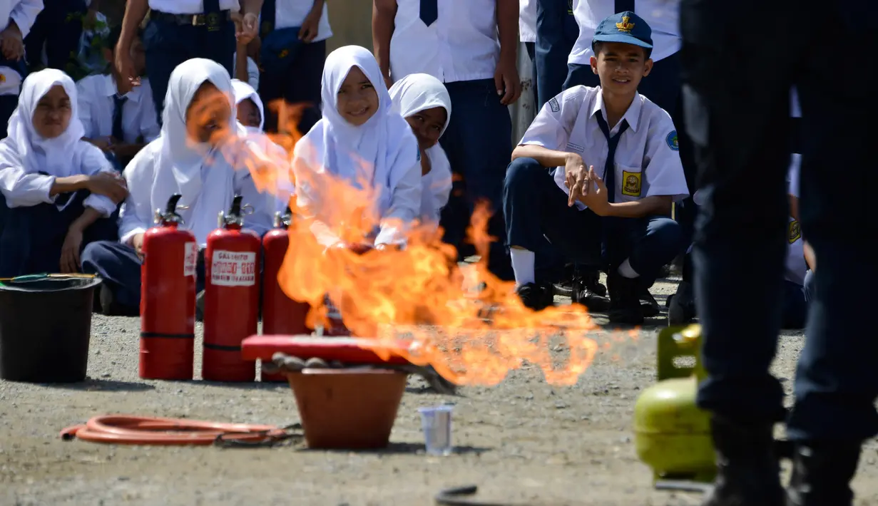 Para siswa menyaksikan petugas pemadam kebakaran memeragakan cara memadamkan api, Banda Aceh, Senin (11/11/2019). Sebanyak 439 pelajar mendapat pembekalan cara pencegahan pemadaman api akibat kebakaran dari petugas Dinas Pemadam Kebakaran dan Penyelamatan Kota Banda Aceh. (CHAIDEER MAHYUDDIN/AFP)