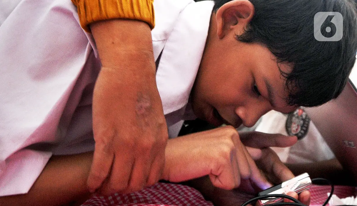 Murid SLB melakukan scaning jari saat tes STIFIn di Sekolah Luar Biasa A Pembina Tingkat Nasional, Lebak Bulus, Jakarta, Selasa (17/12/2019). Tes ini untuk mengetahui minat dan bakat siswa serta merupakan pilot project pertama bagi murid-murid berkebutuhan khusus. (merdeka.com/Arie Basuki)