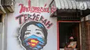 Warga berada di dekat mural bertuliskan "Indonesia terserah", di Kutabumi, Tangerang, Banten, Senin (27/5/2020). Mural dibuat sebagai bentuk kritik terhadap masyarakat yang tetap beraktivitas di luar ruangan tanpa prosedur protokol kesehatan di tengah wabah COVID-19. (Liputan6.com/Angga Yuniar)