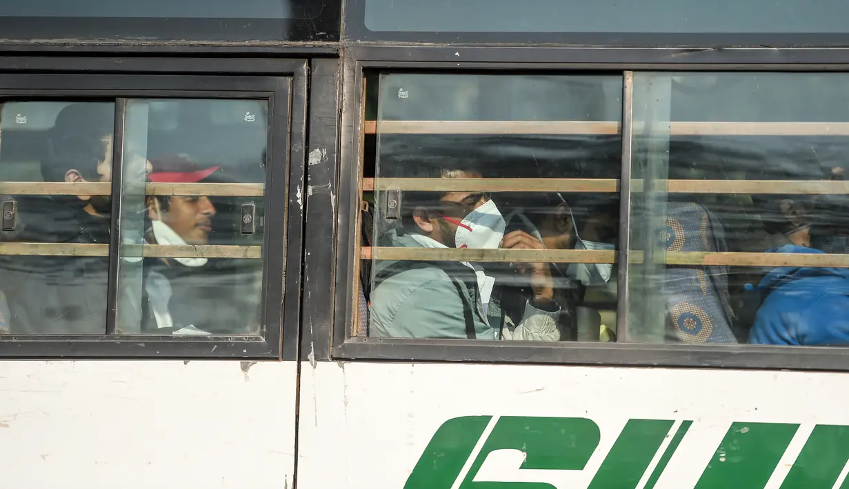 Warga negara India diangkut dengan bus keluar dari Bandara Internasional Indira Gandhi setelah dievakuasi dari kota Wuhan di China, di New Delhi (1/2/2020). India mengevakuasi sekitar 250 warganya dari Wuhan, kota di Hubei yang merupakan pusat wabah virus corona. (AFP/Money Sharma)