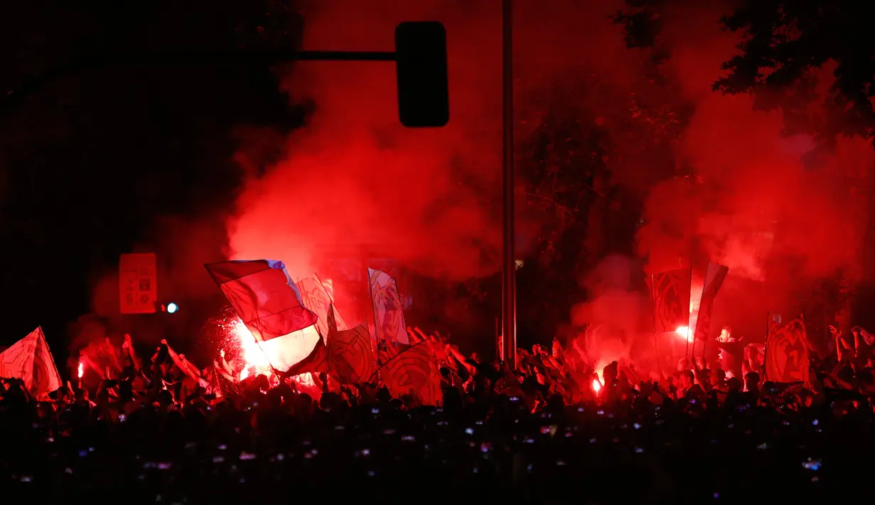 Suporter Real Madrid menyalakan kembang api menyambut tim kesayangnya merayakan gelar juara La Liga di alun-alun Cibeles, Madrid, Spanyol (22/5). Los Blancos mengamankan titel ke-33 sepanjang sejarah usai mengalahkan Malaga 2-0. (AP Photo/Francisco Seco)