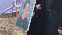 Camillia Laetitia Azzahra atau Zara didampingi sang ibu, Atalia Praratya membawa lukisan wajah Eril yang tersenyum saat mengantar kepergian Eril menuju tempat peristirahatan terakhir. (Instagram/ataliapr)