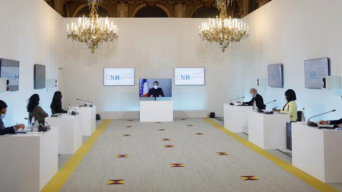 Presiden Prancis Emmanuel Macron terlihat di layar saat dia menghadiri konferensi Kemanusiaan Nasional (NHC), di Kementerian Luar Negeri di Paris, Kamis (17/12/2020). Presiden Macron akan lanjut kerja di kediamannya setelah positif Covid-19. (Charles Platiau/Pool via AP)