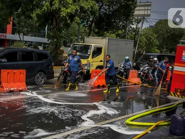 Sejumlah personil pemadam kebakaran membersihkan tumpah oli yang terjadi di Jalan Veteran depan Gedung Krida Bakti, Jakarta, Kamis (16/1/2020). Petugas damkar  melakukan pembersihan dengan cairan deterjen maupun campuran khusus agar jalan tersebut tidak lagi licin. (Liputan6.com/Faizal Fanani)