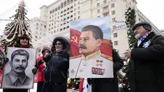 Orang-orang berfoto sambil memegang potret pemimpin Soviet Josef Stalin sebelum meletakkan bunga di makamnya menandai peringatan 142 tahun kelahirannya di dekat Tembok Kremlin di Lapangan Merah di Moskow, Rusia, Selasa (21/12/2021). (AP Photo/Alexander Zemlianichenko)