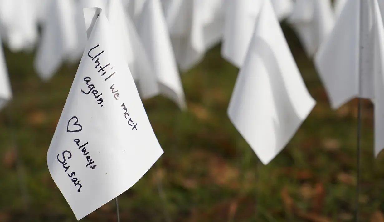 Sebuah bendera putih dengan pesan ditanam untuk mengenang warga Amerika yang meninggal karena COVID-19 di dekat Stadion RFK di Washington, Selasa (27/10/2020). Instalasi seni Suzanne Brennan Firstenberg itu disebut "In America, How Could This Happen.” (AP/Patrick Semansky)