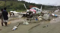 Sebuah pesawat twin otter rusak pasca terseret banjir bandang dan menutupi lapangan terbang di Kabupaten Sentani, Jayapura, (17/3). Banjir bandang Sentani menewaskan 70 orang dan puluhan luka-luka. (AFP/Netty Dharma Somba)