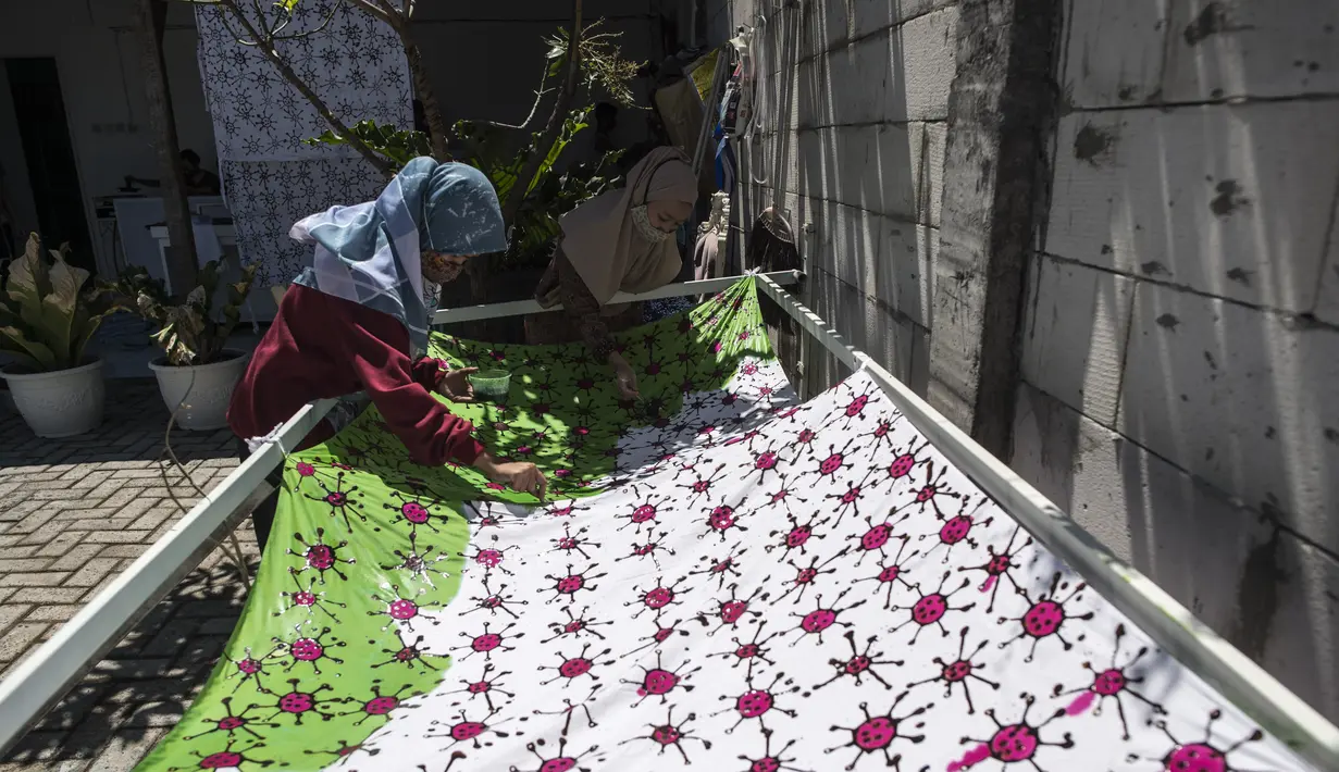 Penyandang disabilitas menjemur kain batik dengan motif virus corona di Surabaya, Jawa Timur (19/8/2020). Di tengah pandemi Covid-19, sekelompok penyandang disabilitas di Surabaya membuat batik bermotifkan virus corona. (AFP/JUNI KRISWANTO)