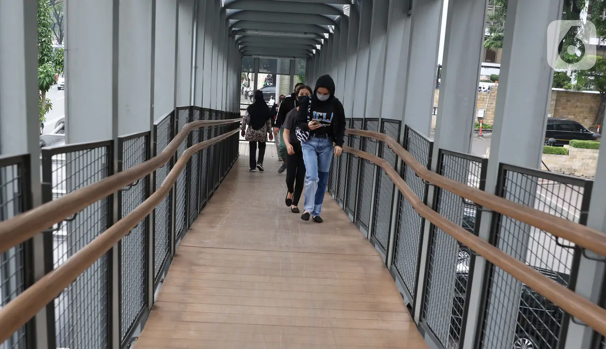 Warga mengenakan masker melintas di JPO Jalan Jenderal Sudirman, Jakarta, Kamis (9/7/2020). Berdasar data yang diumumkan pemerintah pada Kamis (9/7) ada penambahan 2.657 orang yang terinfeksi COVID-19 sehingga jumlah penderita menjadi 70.736. (Liputan6.com/Helmi Fithriansyah)