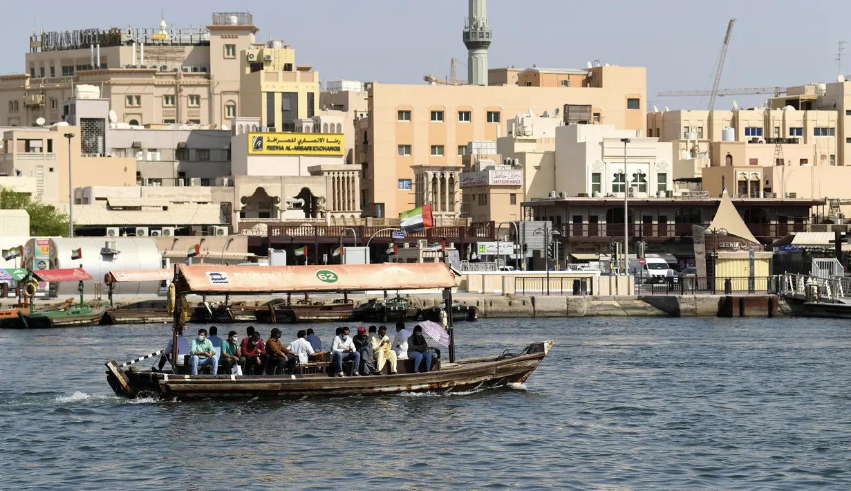 Orang-orang naik perahu di atas kapal kayu tradisional di dekat Deira Souk di Teluk Emirat Dubai (30/9/2020). (AFP/Karim Sahib)