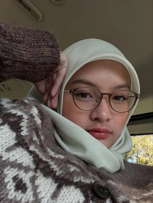 Pilihan hijab polos berwarna pastel terlihat serasi dengan wajahnya yang cantik natural. Aisha juga memadukannya dengan busana bermotif dan kacamata bergaya klasik yang menambah kesan cerdas sekaligus feminin. Penampilan ini memberikan kesan matang, tetapi tetap memancarkan aura imut khas remaja. (Liputan6.com/IG/@khadeejaisha)