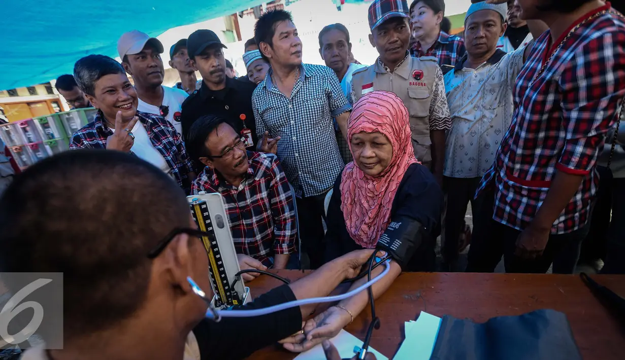 Cawagub petahana Djarot Saiful Hidayat mendampingi warga yang sedang melakukan pemeriksaan kesehatan di Jembatan Besi, Jakarta (15/1). Selain memberi pengobatan gratis, Djarot juga berdiaolg dengan warga setempat. (Liputan6.com/Faizal Fanani)