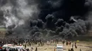 Kepulan asap hitam membubung di pagar perbatasan Palestina-Israel di kota Gaza tengah (13/4). Ratusan warga Palestina membakar ban saat melakukan unjuk rasa di perbatasan Palestina-Israel. (AFP/Mohammed Abed)