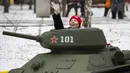 Seorang wanita melambai ke kerabat ketika dia mengendarai model tank T-34 era Soviet yang legendaris di objek wisata petualangan anak-anak Tankodrom di taman Sokolniki di Moskow, Rusia (6/1/2020). (AP Photo/Alexander Zemlianichenko)