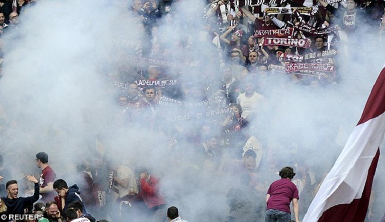 Penggemar Torino yang ditelan oleh asap setelah flare dilemparkan ke kerumunan selama derby Turin. (Dailymail)