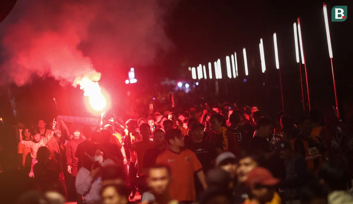 <p>Pendukung Persija Jakarta menyalakan suar saat berjalan menuju stadion untuk menyaksikan laga terakhir BRI Liga 1 2022/2023 antara Persija Jakarta melawan PSS Sleman di Stadion Utama Gelora Bung Karno (SUGBK), Senayan, Jakarta, Sabtu (15/04/2023). (Bola.com/Bagaskara Lazuardi)</p>