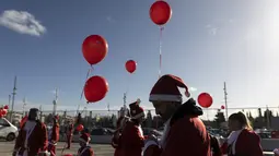 Orang-orang yang mengenakan kostum Sinterklas bersiap untuk ambil bagian dalam Athens Santa Run, di Athena, Yunani, Minggu (12/12/2021). Ratusan orang berpartisipasi mengikuti lomba lari untuk acara amal di area sekitar kompleks Stadion Olimpiade Athena. (AP Photo/Yorgos Karahalis)