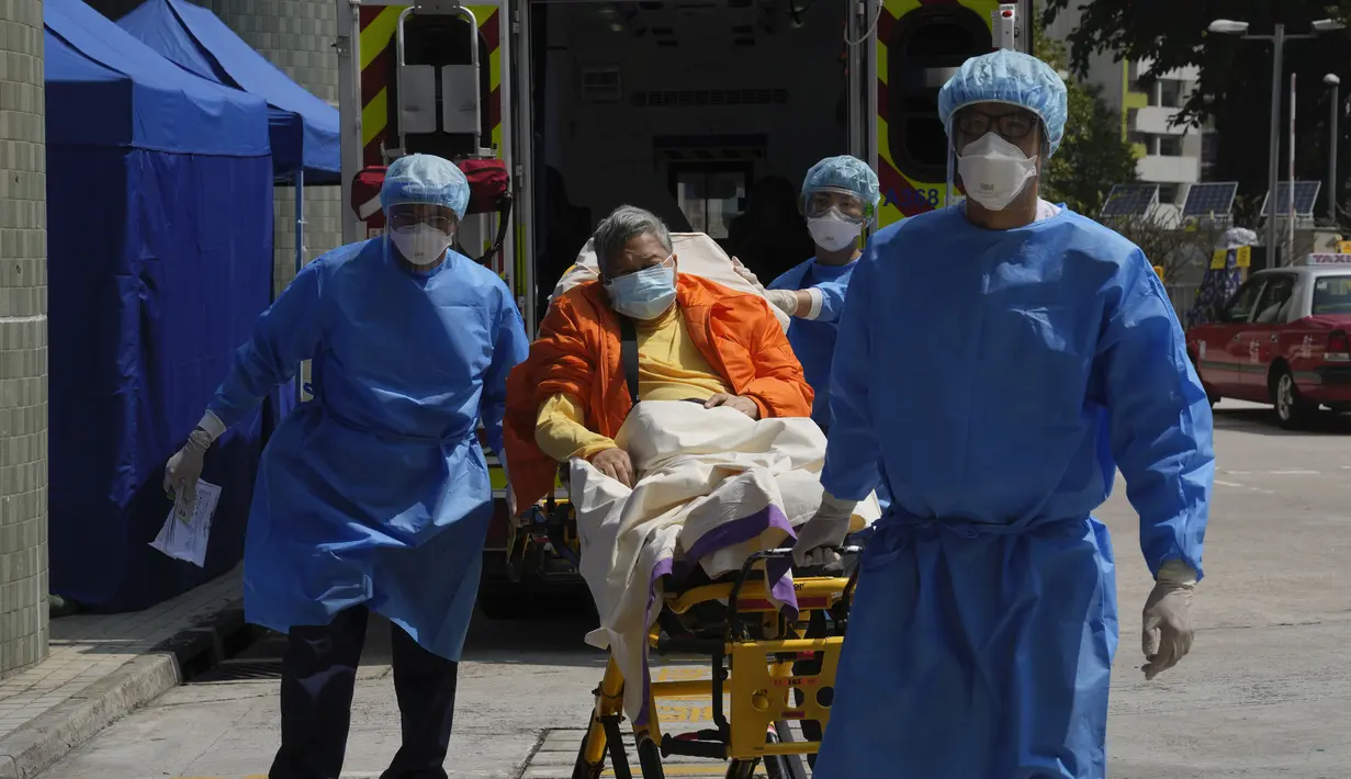 Seorang pasien di tempat tidur rumah sakit dibawa menuju ruang tunggu sementara di luar Caritas Medical Center, Hong Kong, Rabu (2/3/2022). Beberapa orang terpaksa menunggu di luar rumah sakit karena saat ini sedang kelebihan beban dengan kemungkinan pasien terinfeksi COVID. (AP Photo/Kin Cheung)