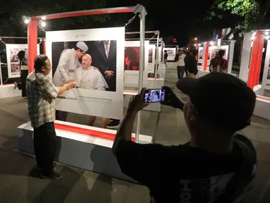 Pengunjung memperhatikan foto yang dipamerkan pameran foto para pemenang Anugerah Pewarta Foto Indonesia (APFI) 2025 di Loji Gandrung, Solo, Jawa Tengah, Jumat (25/4/2025). (merdeka.com/Arie Basuki)