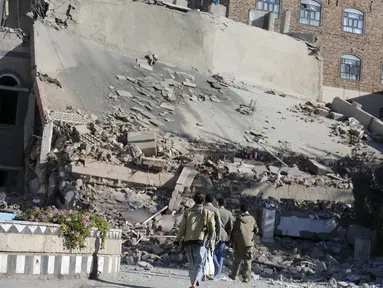 Militan Houthi saat melihat reruntuhan bangunan markas Perdagangan dan Industri yang hancur di Sanaa, Yaman, (5/1). Bangunan ini hancur setelah  mendapat serangan udara dari Arab Saudi. (REUTERS / Khaled Abdullah)