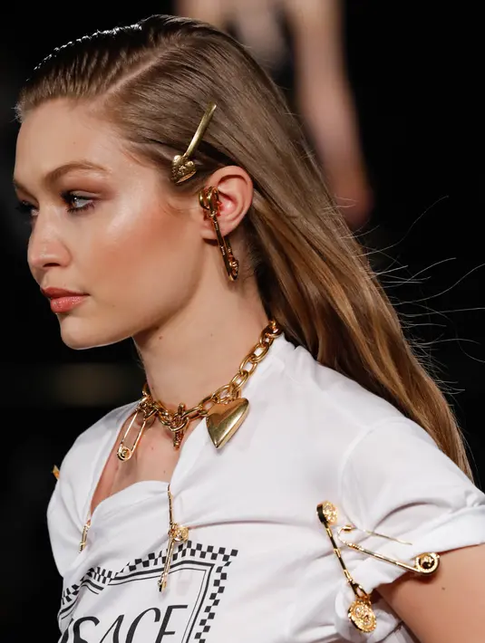Model Gigi Hadid memperagakan busana koleksi Versace Pre-Fall 2019 di New York (2/12). Gigi Hadid tampil dengan berbagai kalung dan pin saat berjalan di atas catwalk. (AFP Photo/JP Yim)