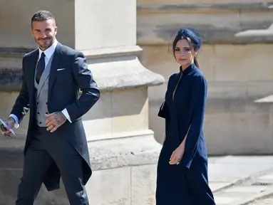 Gaya mantan pemain sepak bola Inggris, David Beckham dan sang istri Victoria Beckham saat menghadiri pernikahan Pangeran Harry dan Meghan Markle di St. George's Chapel, Kastil Windsor, Inggris, Sabtu (19/5). (TOBY MELVILLE/POOL/AFP)