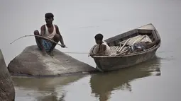 Seorang nelayan duduk di atas batu menangkap ikan di sungai Brahmaputra di desa Kasoshila di Gauhati, India (21/10/2019). Brahmaputra adalah salah satu sungai terbesar di Asia, yang melewati wilayah Tibet China, India, dan Bangladesh sebelum konvergen ke Teluk Benggala. (AP Photo/Anupam Nath)