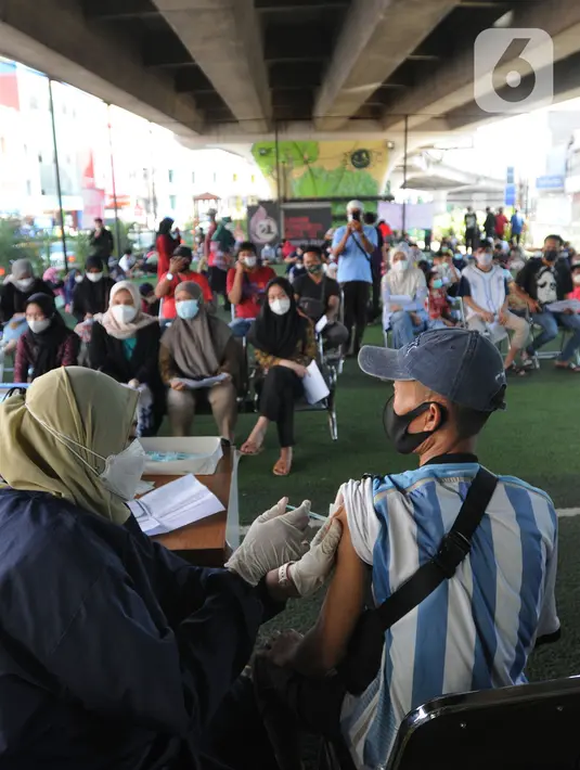 Petugas kesehatan menyuntikkan vaksin dosis ketiga kepada seorang pria di kolong flyover Ciputat, Tangerang Selatan, Sabtu (2/4/2022). Selain untuk melengkapi vaksin COVID-19, booster menjadi syarat perjalanan mudik lebaran tahun 2022. (merdeka.com/Arie Basuki)