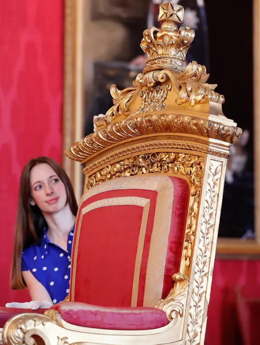 Pekerja berpose dengan singgasana milik Ratu Victoria sebagai bagian dari pameran di Istana Buckingham, London, Rabu (17/7/2019). Pameran yang dibuka pada 20 Juli tersebut menandai peringatan 200 tahun kelahiran Ratu Victoria. (AP Photo/Frank Augstein)