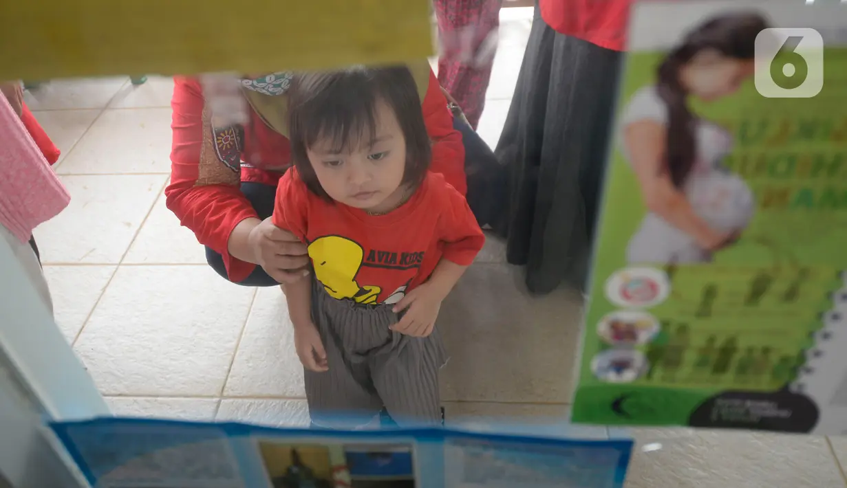 Seorang anak menunggu untuk divaksin di Posyandu RW 09, Pondok Benda, Tangerang Selatan, Senin (14/12/2020). Program rutin pemerintah setiap bulan ini digelar lewat posyandu dengan penyuluhan dan perawatan anak agar tumbuh kembangnya sehat. (merdeka.com/Dwi Narwoko)