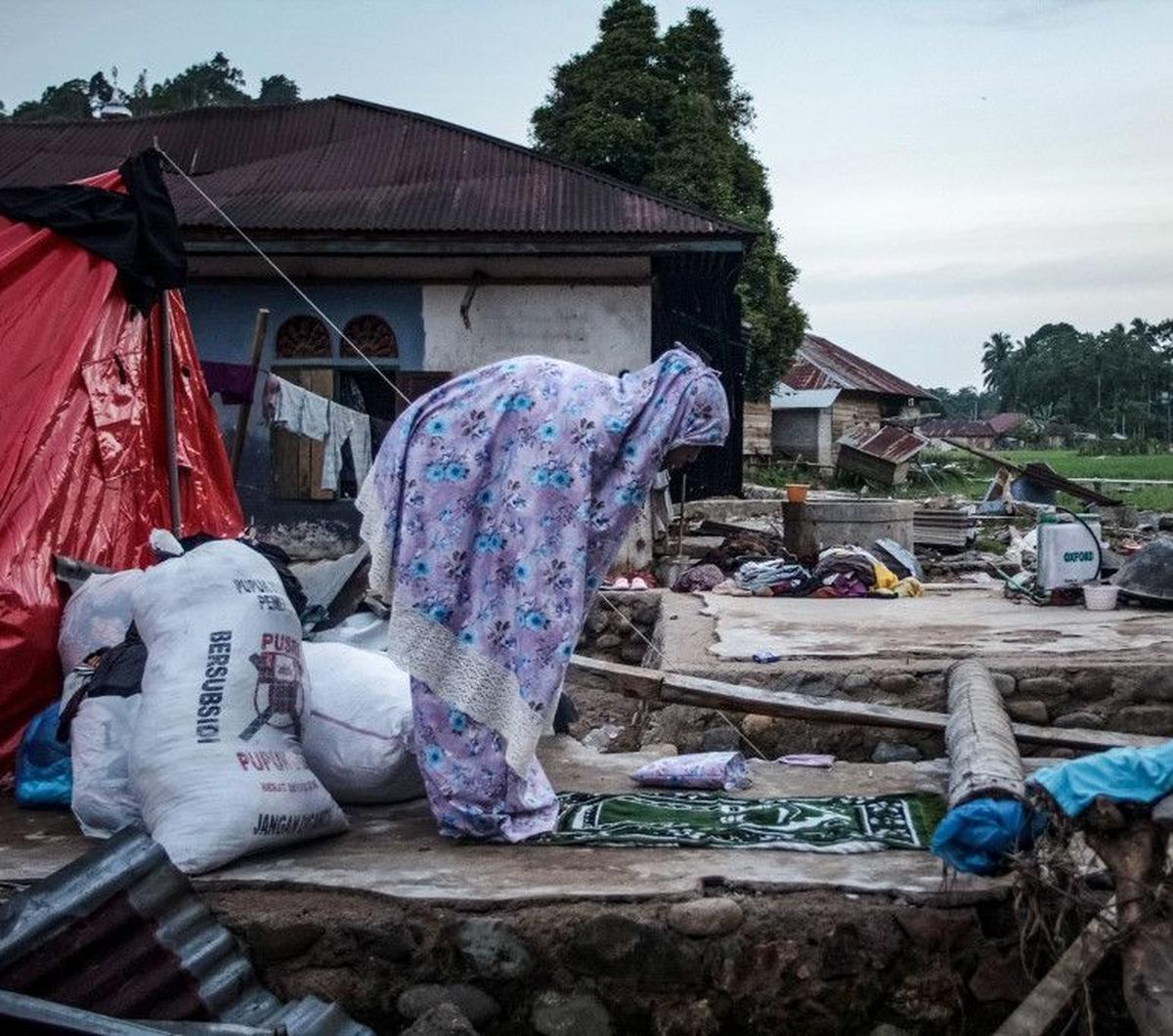 Seorang warga menunaikan ibadah salat maghrib seusai berbuka puasa Ramadan di dekat puing bangunan yang runtuh akibat terjangan banjir bandang di Ganting, Pesisir Selatan, Sumatera Barat, pada 14 Maret 2024. Terjangan banjir bandang di Ganting, Pesisir Se