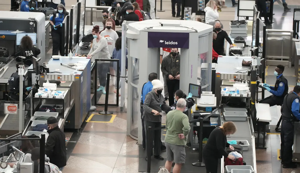 Pelancong mengantre untuk melewati pos pemeriksaan keamanan selatan di terminal Bandara Internasional Denver di Denver (26/12/2021). Maskapai menunda ratusan penerbangan pada Minggu (26/12). (AP Photo/David Zalubowski)