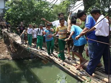 Sejumlah pelajar menyeberangi Kali Angke melewati jembatan rapuh di Kampung Cantiga, Petir, Cipondoh, Tangerang, Rabu (2/9/2015). Jembatan berusia lima tahun tersebut menghubungkan Cipondoh dan Kembangan, Jakarta. (Liputan6.com/Gempur M Surya)