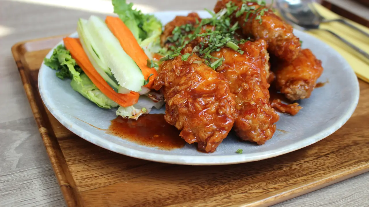Ilustrasi hidangan Korean fried chicken dengan saus gochujang yang menggugah selera.